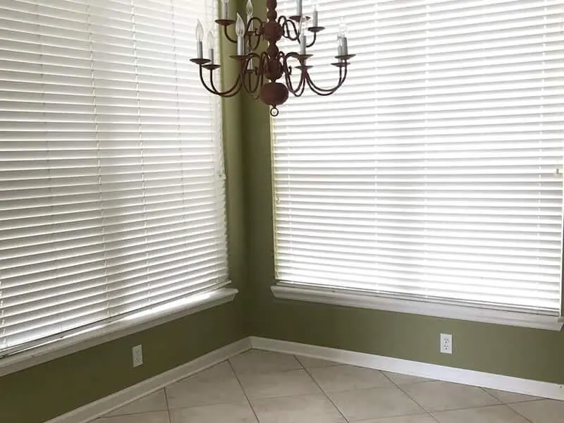Room corner with white blinds and a green wall